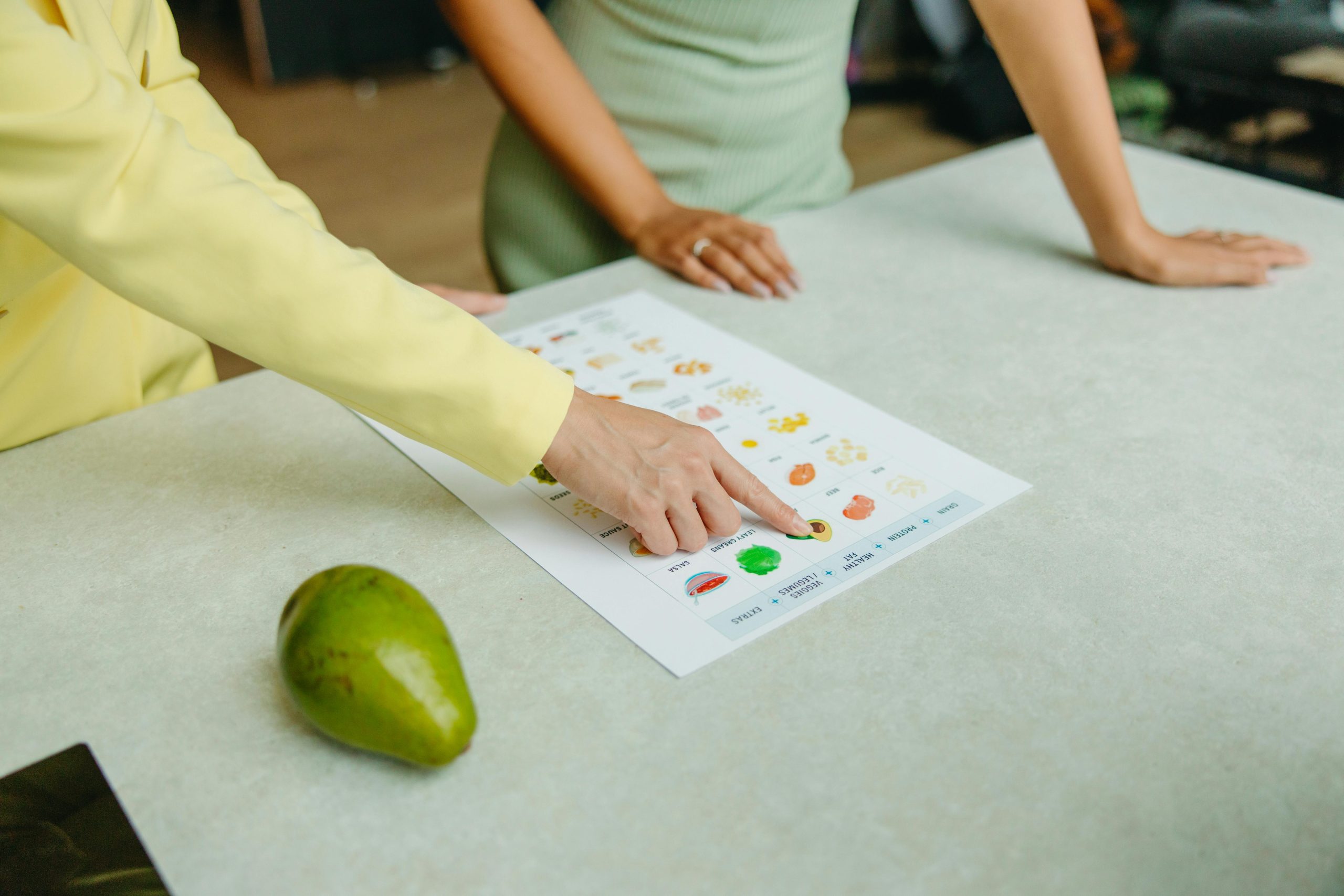 Person pointing to diet plan on paper.
